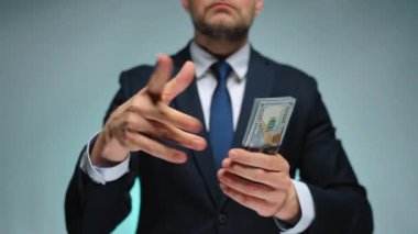 Resmi olarak giyinmiş bir adam Amerikan Doları 'nı kameraya doğru fırlatıyor. Yatırım, başarı, finansal beklentiler veya kariyer ilerlemesi kavramı.
