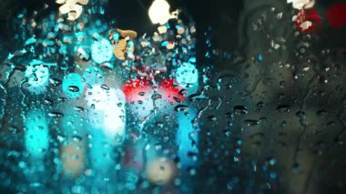 Akşam şehrinin çok renkli ışıkları ve yağmurlu bir pencereden geçen arabalar. Yağmurlu depresif hava