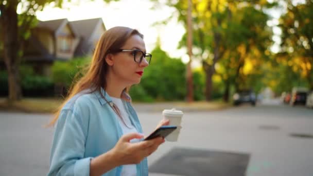 Ευτυχισμένη Γυναίκα Smartphone Και Τον Καφέ Στα Χέρια Της Περπατά — Αρχείο Βίντεο