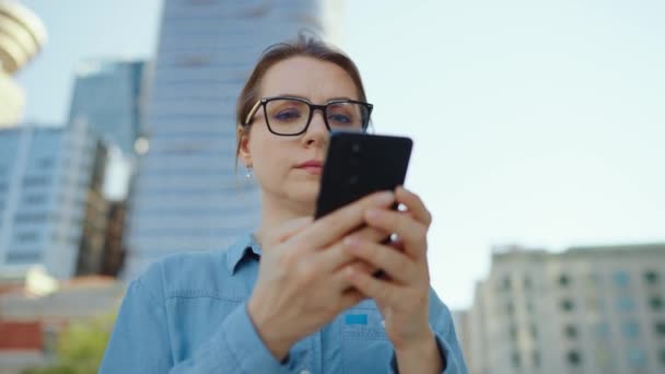 Biała Kobieta Okularach Stoi Ulicy Mieście Używa Smartfona Drapacze Chmur — Wideo stockowe