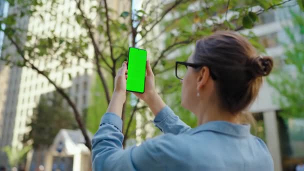 Femme est debout dans la rue et fait une photo par smartphone avec écran vert. Mouvement lent.