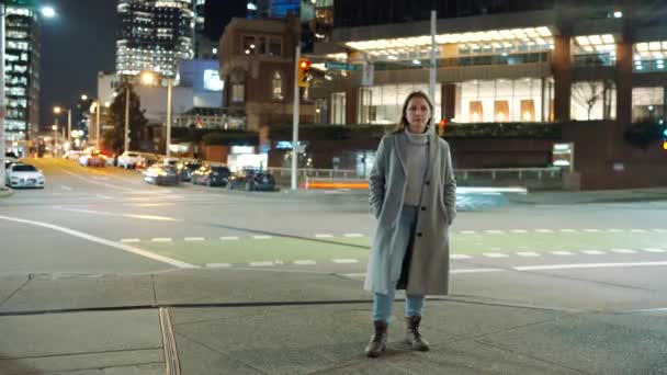 夜の街路に立っている女性の時間の経過と 認識できない人々や車の速い移動シルエット ストック映像