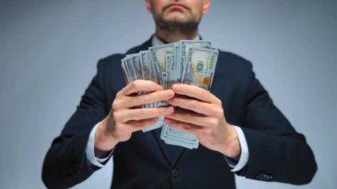 Resmi olarak giyinmiş bir adam Amerikan dolarlarını sayıyor, yakın plan. Yatırım, başarı, finansal beklentiler veya kariyer ilerlemesi kavramı.