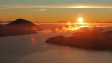 Vancouver 'ın kuzeyindeki güzel günbatımında deniz manzarası. Howe 'daki fiyortlar. Dağların siluetlerinin üzerine güneş batıyor. British Columbia, Kanada.