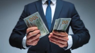 Resmi olarak giyinmiş bir adam Amerikan dolarlarını sayıyor, yakın plan. Yatırım, başarı, finansal beklentiler veya kariyer ilerlemesi kavramı.