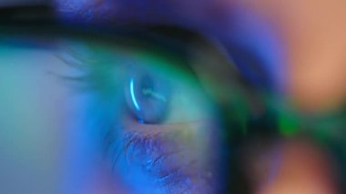 Gözlüklü kadın monitöre bakıyor ve veri ve analizlerle çalışıyor. Monitör ekranı gözlüklere yansıyor. Aşırı yakın çekim.