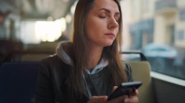 Toplu taşıma. Tramvayda akıllı telefon kullanan, arkadaşlarıyla mesajlaşan bir kadın. Şehir, şehir, ulaşım.