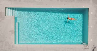 Kırmızı mayo giymiş bir kadının havuzda sırt üstü yatışı. Rahatlatıcı konsept, yaz yaşam tarzı