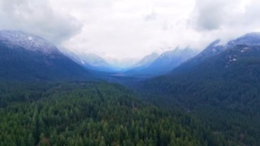 Kış mevsiminde çarpıcı dağ manzarasının havada hızlanması. Dağlar kar ve bulutlarla kaplıdır. Vancouver, British Columbia, Kanada yakınlarında çekilmiş..