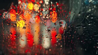 Akşam şehrinin çok renkli ışıkları ve yağmurlu bir pencereden geçen arabalar. Yağmurlu depresif hava