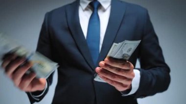 Resmi olarak giyinmiş adam Amerikan dolarlarını sayıyor, yakın plan. Yatırım, başarı, finansal beklentiler veya kariyer ilerlemesi kavramı.