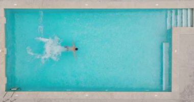 Top down view as a man dives into the pool and swims. Slow motion
