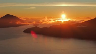 Vancouver 'ın kuzeyindeki güzel günbatımında deniz manzarası. Howe 'daki fiyortlar. Dağların siluetlerinin üzerine güneş batıyor. British Columbia, Kanada.