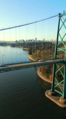 Şafakta Lions Gate Köprüsü ve Stanley Parkı 'nın havadan görüntüsü. Arka planda Vancouver şehir merkezi var. Britanya Kolombiyası Kanada. Dikey video