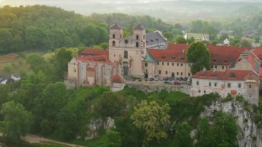Polonya 'nın Tyniec kentindeki Benedictine Manastırı' nın şafak vakti havadan görünüşü. Katolik manastırının eski mimarisi. Kuleleri, kırmızı çatıları, dini ve tarihi su üzerindeki kayalar. Yörünge atışı
