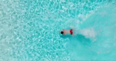 Top down view as a man dives into the pool and swims. Slow motion