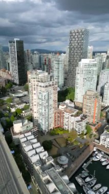 Vancouver, Granville köprüsü, False Creek ve marina, British Columbia, Kanada 'daki gökdelenlerin hava görüntüsü. Çarpıcı bulutlu gökyüzü. Dikey video. Hız rampası