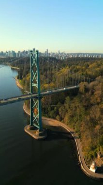 Şafakta Lions Gate Köprüsü ve Stanley Parkı 'nın havadan görüntüsü. Arka planda Vancouver şehir merkezi var. Britanya Kolombiyası Kanada. Dikey video