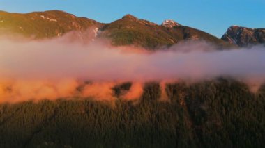 Gün batımında bulut seviyesindeki dağların havadan görünüşü. Squamish ve Vancouver, British Columbia, Kanada