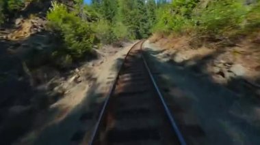 FPV insansız hava aracı demiryolu üzerinde hızla ilerliyor. Demiryolunun her iki tarafını da çevreleyen ağaçlar. Seyahat konsepti. British Columbia, Kanada