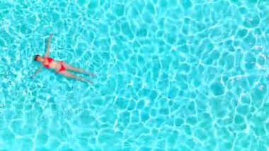 Pembe mayo giymiş bir kadının havuzda sırt üstü yatışı. Rahatlatıcı konsept, yaz yaşam tarzı. Havuz ve çöl manzarası.
