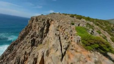 Deniz kıyısında kayalara ve suya yakın çevik bir uçuş. Güney Sardunya, İtalya. FPV insansız hava aracı tarafından filme alındı.