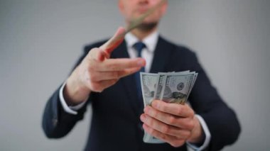 Resmi olarak giyinmiş bir adam Amerikan Doları 'nı kameraya doğru savuruyor. Yatırım, başarı, finansal beklentiler veya kariyer ilerlemesi kavramı.