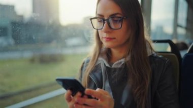 Toplu taşıma. Tramvayda akıllı telefon kullanan, arkadaşlarıyla mesajlaşan bir kadın. Şehir, şehir, ulaşım.