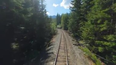 FPV insansız hava aracı demiryolu üzerinde hızla ilerliyor. Demiryolunun her iki tarafını da çevreleyen ağaçlar. Seyahat konsepti. British Columbia, Kanada