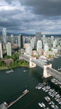 Vancouver, Granville köprüsü, False Creek ve marina, British Columbia, Kanada 'daki gökdelenlerin hava görüntüsü. Çarpıcı bulutlu gökyüzü. Dikey video
