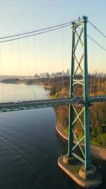 Şafakta Lions Gate Köprüsü ve Stanley Parkı 'nın havadan görüntüsü. Arka planda Vancouver şehir merkezi var. Britanya Kolombiyası Kanada. Dikey video.