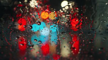 Akşam şehrinin çok renkli ışıkları ve yağmurlu bir pencereden geçen arabalar. Yağmurlu depresif hava