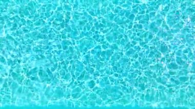 Yüzme havuzundaki saf mavi suyun yüzeyinde ışık yansımaları var. Hava görüntüleri, yukarıdan aşağıya doğru. Yavaş çekim