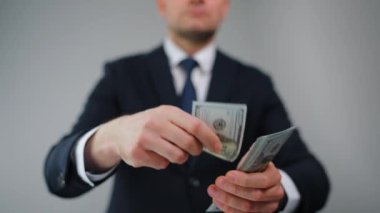 Resmi olarak giyinmiş bir adam Amerikan Doları 'nı kameraya doğru savuruyor. Yatırım, başarı, finansal beklentiler veya kariyer gelişimi kavramı. Yavaş çekim