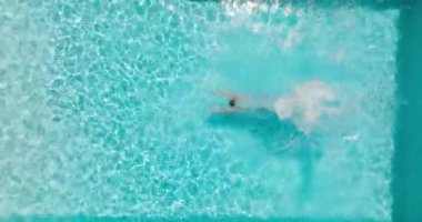 Top down view as a man dives into the pool and swims. Slow motion