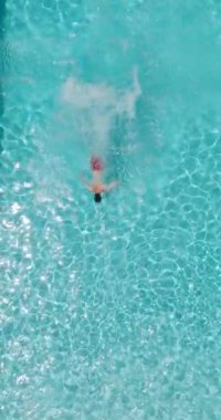 Bir adamın havuza dalıp, yavaş çekimde yüzdüğü tepeden aşağı bir manzara.