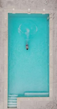 Bir adamın havuza dalıp, yavaş çekimde yüzdüğü tepeden aşağı bir manzara.