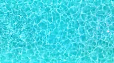 Yüzme havuzundaki saf mavi suyun yüzeyinde ışık yansımaları var. Hava görüntüleri, yukarıdan aşağıya doğru. Yavaş çekim