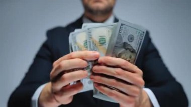 Mutlu giyinmiş adam Amerikan Doları 'nın faturalarını hızlı bir şekilde sayıyor. Yatırım, başarı, finansal beklentiler veya kariyer ilerlemesi kavramı.