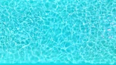 Yüzme havuzundaki saf mavi suyun yüzeyinde ışık yansımaları var. Hava görüntüleri, yukarıdan aşağıya doğru. Yavaş çekim