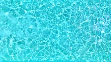 Yüzme havuzundaki saf mavi suyun yüzeyinde ışık yansımaları var. Hava görüntüleri, yukarıdan aşağıya doğru. Yavaş çekim