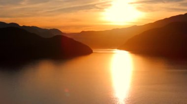 Vancouver 'ın kuzeyindeki güzel günbatımında deniz manzarası. Dağların siluetlerinin üzerine güneş batıyor. British Columbia, Kanada.