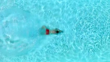 Top down view as a man dives into the pool and swims. Slow motion