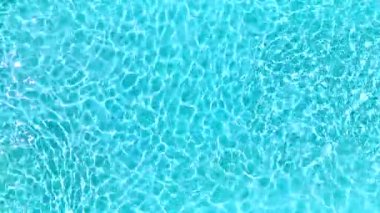 Yüzme havuzundaki saf mavi suyun yüzeyinde ışık yansımaları var. Hava görüntüleri, yukarıdan aşağı görünüm.