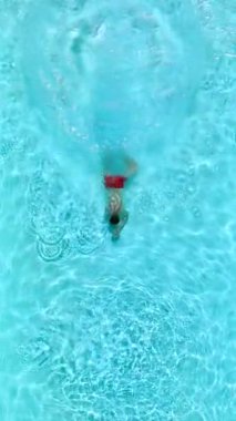 Top down view as a man dives into the pool and swims. Slow motion