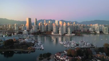 Şehir merkezindeki gökdelenlerin, dağların, False Creek 'in, tekneli marinanın havadan görüntüsü. Vancouver, British Columbia, Kanada, gün batımında.