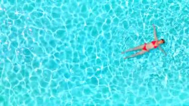 Pembe mayo giymiş bir kadının havuzda sırt üstü yatışı. Rahatlatıcı konsept, yaz yaşam tarzı. 