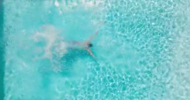 Top down view as a man dives into the pool and swims. Slow motion