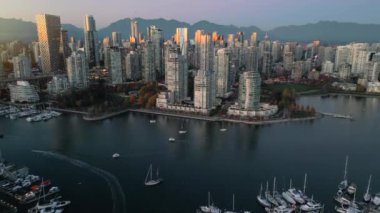 Şehir merkezindeki gökdelenlerin, dağların, False Creek 'in, tekneli marinanın havadan görüntüsü. Vancouver, British Columbia, Kanada, gün batımında.