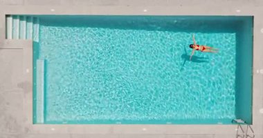 Pembe mayo giymiş bir kadının havuzda sırt üstü yatışı. Rahatlatıcı konsept, yaz yaşam tarzı. 